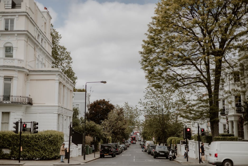 A quiet city street scene near Parsons Green station SW6, featuring white Victorian-style terraced buildings with ornate architectural details and balconies. In the foreground, two black traffic light